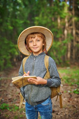 Harika bir yaz ormanında sırt çantalı, Pith kasklı aktif bir çocuk. Macera ve seyahat tutkusu. Boşluğu kopyala.