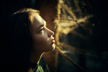 Yeşil elbiseli güzel bir kızın karanlık bir peri ormanında kaybolup kurtuluşu ararken yan görüntüsü. Peri masalı kahramanı. Fantezi.