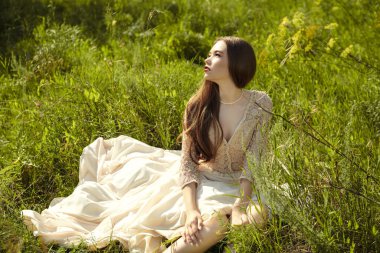 Güzellik ve moda. Güzel dantel elbiseli muhteşem bir kız güneşli bir günde yeşil çimlerin üzerinde dinlenir. Yaz özgürlüğü.