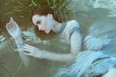 Efsanevi mitler ve efsaneler. Büyüleyici bir su perisi görüntüsü nehrin sularında yatıyor. Fantezi.