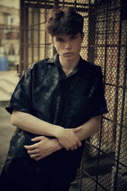 Siyah elbiseli modern bir genç büyük bir şehrin karanlık bir sokaktaki metal bir ızgaraya yaslanmış duruyor. Kentsel yaşam tarzı.