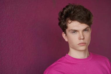 Mor bir arka planda, kırmızı bir kazakla fotokopi çeken modern bir mankenin portresi. Gençlik modası. Erkek saç stilleri.