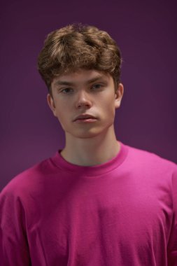 Gençlik modası. Mor arka planda kırmızı bir sweatshirt giyen modern bir erkek modelin portresi. Erkek saç stilleri.