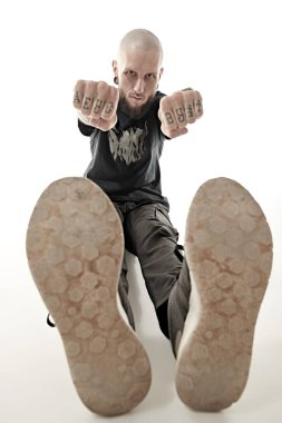 Antisosyal davranış, protesto ifadesi. Gayri resmi görünüşlü zalim bir adam yumruklarını kameraya doğru uzatıyor ve kameraya meydan okuyarak bakıyor. Beyaz stüdyo geçmişi.