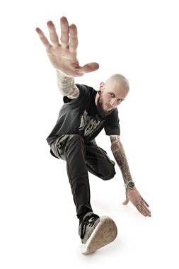 Rock müzisyeni. Gayri resmi görünüşlü, kafası kazınmış, dudağında ve kulaklarında piercing olan, vücudunda dövmesi olan bir adam stüdyoda siyah giysiler içinde poz veriyor. Beyaz stüdyo geçmişi.