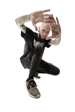 Rock müzisyeni. Gayri resmi görünüşlü, kafası kazınmış, dudağında ve kulaklarında piercing olan, vücudunda dövmesi olan bir adam stüdyoda siyah giysiler içinde poz veriyor. Beyaz stüdyo geçmişi.