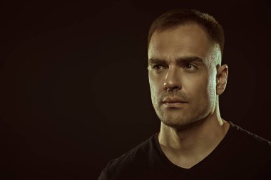 Yakışıklı, güçlü, kendine güvenen bir adam geleceğe bakar. Siyah bir arkaplanda, metin için yeri olan bir stüdyo resmi. İnsanlar ve duygular. Yaşam tarzı, seçimler. Spor..