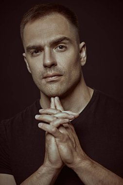 Yakışıklı kaslı bir adam sakince kameraya bakar. Siyah arka planda stüdyo portresi. İnsanlar ve duygular. Yaşam tarzı, seçimler. Spor..