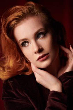 Pahalı kadife ceketli, loş ışıklı bir odada kızıl saçlı çekici bir genç kadın. Moda ve kadınlık. Kadın güzelliği ve tarzı. Oklu zarif bir makyaj. Zarif saç stili..