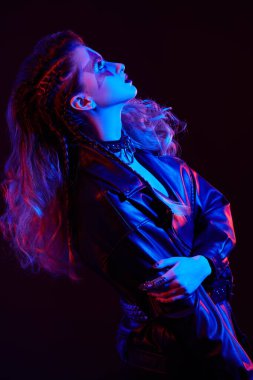 Parlak makyajlı ve parlak rock tarzı saçı olan bir rock yıldızı renkli sahne ışıklarıyla gösteri yapıyor.. 