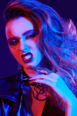 Parlak parlak makyajlı ve parlak rock tarzı renkli sahne ışıklarıyla saçı olan bir rock yıldızının yakın çekimi. Rock and Pop müziği. 
