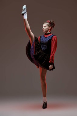 Ulusal İrlanda kostümü giymiş profesyonel bir dansçı kadının geleneksel İrlanda dansını sergilediği bir stüdyo resmi..