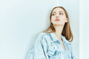 Denim Fashion. Beyaz bir stüdyonun arka planında çıplak omuzlarıyla poz veren çekici sarışın bir kadının portresi. Kadın güzelliği.