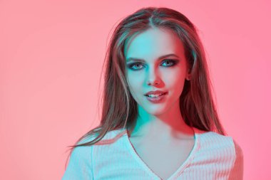 Gençlik partisi görünüşü. Çekici bir genç kızın portresi koyu renkli dumanlı gözleri ve pembe arka planda uzun taranmış saçları var. Güzellik, makyaj malzemesi ve saç stili. Boşluğu kopyala.