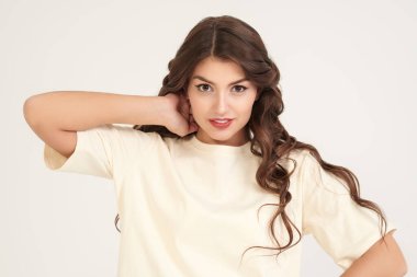 İnsanlar, mutlu duygular. Uzun kıvırcık saçlı, mutlu ve heyecanlı bir şekilde gülümseyen güzel bir kızın portresi. Fotokopi alanı olan beyaz stüdyo. Kadın güzelliği.