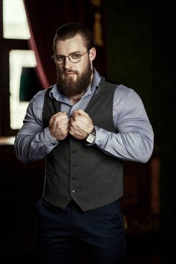 Başarılı bir iş adamı. Klasik, saygıdeğer takım elbiseli, iç mimarisinde yelek ve gömlek olan yakışıklı, bakımlı bir erkek. Erkek saç stili ve sakalı. Erkek güzelliği ve moda.