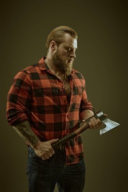 Ekose gömlekli, baltalı, vahşi sakallı bir adamın portresi. Koyu gri stüdyo geçmişi. Erkek güzelliği ve erkeklik. Berber dükkanı reklamı.