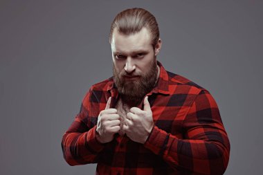 Gri bir stüdyo arka planında ekose gömlekli, sakallı yakışıklı bir adamın portresi. Erkek güzeli. Berber dükkanı reklamı. Erkeklik ve güç.