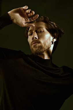 Siyah bir kazak giymiş, 40 yaşında, yakışıklı, kıvırcık saçlı, düşünceli, düşünceli bir adamın koyu renk bir anahtarındaki resim. İnsanlar, duygular. Erkeklerin psikolojisi.