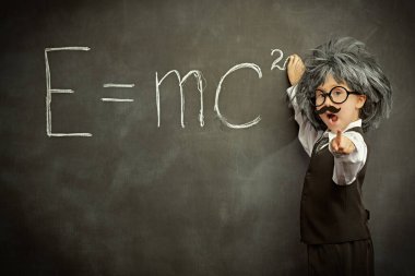 Alışılmışın dışında düşün. Gözlüklü, bıyıklı ve peruklu sevimli bir çocuk, küçük bir fizik profesörü gibi poz veriyor. Siyah karatahta arka planı. Eğitim ve erken kalkınma.