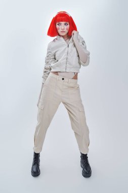 Parlak kırmızı makyajlı ve şık kızıl saçlı çekici bir bilimkurgu cyborg kızın tam boy portresi. Siber punk konsepti. Beyaz arkaplan. 