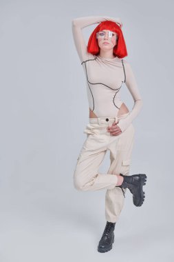 Parlak kırmızı makyajlı ve şık kızıl saçlı çekici bir bilimkurgu cyborg kızın tam boy portresi. Siber punk konsepti. Beyaz arkaplan. 