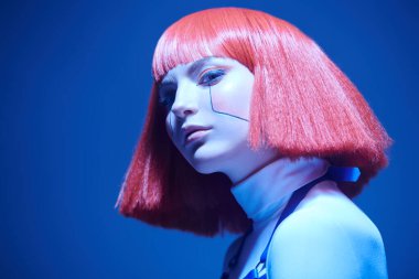 Siber punk konsepti. Parlak kırmızı makyajlı, kızıl saçlı, siyah ışıkta poz veren güzel bir siber punk kızı portresi. Sanal oyunlar. Makyaj ve saç stili. 