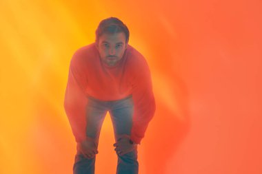 Yakışıklı, olgun bir adamın sanat portresi. Kamerayı dört gözle bekliyor. Portakal ışığında puslu bir stüdyo portresi. Psikoloji, duygular.