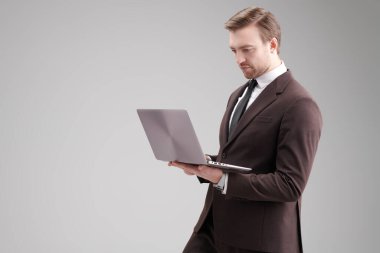 Klasik takım elbiseli ve dizüstü bilgisayarlı orta yaşlı bir iş adamının portresi. Başarılı insanlarız. İş stili. Gri arkaplanda fotokopi alanı olan bir stüdyo portresi.