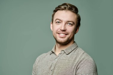 Kameraya gülümseyen orta yaşlı bir adamın portresi. İnsanlar, duygular. Erkek sağlığı ve güzelliği. Fotokopi alanı olan gri bir arkaplanda stüdyo resmi. 