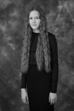 Siyah-beyaz, uzun kahverengi saçlı, koyu renk stüdyo arka planında iri gözlü güzel bir kızın portresi. Çocukların düşünceleri ve psikolojisi.