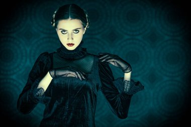 Gotik roman, mistisizm. Seçkin siyah kadife elbiseli ve dantel eldivenli esmer kız portresi, gecenin karanlığında fotokopi alanı olan eskimiş bir arka planda duruyor. Makyaj ve saç stili.