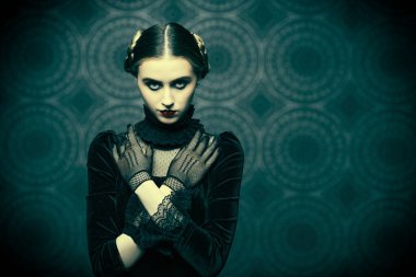 Makyaj ve saç stili. Gotik roman, mistisizm. Şık siyah kadife elbiseli ve dantel eldivenli dramatik esmer kızın portresi, gecenin karanlığında fotokopi çekilen bir arka planda duruyor..