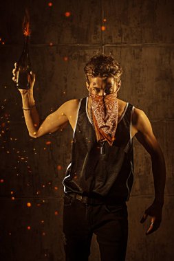 Yüzünde yaralar ve yüzünü kapatan bandana elinde bir yangın bombası tutan kararlı bir adam. Grev, devrim. Aksiyon filmi kahramanı.