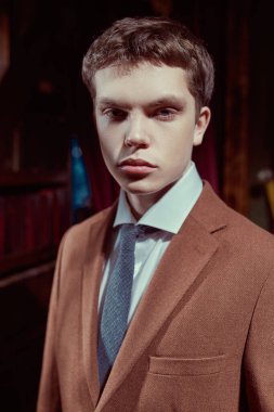 Pahalı takım elbiseli saygıdeğer bir genç adam zengin bir dairede klasik bir iç mimarisi ile duruyor. Erkek modası, lüks tarzı..