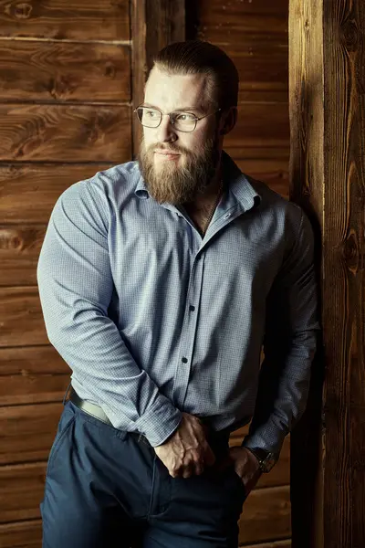 Ahşap arka planda yelek ve tişörtü olan saygıdeğer, klasik takım elbiseli yakışıklı bir erkek. Erkek saç stili ve sakalı. Erkek güzelliği ve moda. Başarılı iş adamı. 