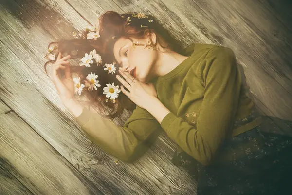 Bahar ve yaz havası. Dalgalı saçlı, tahta bir zeminde uzanmış, saçlarında beyaz çiçeklerle güzel bir kız. Doğal kozmetikler. Kadın güzelliği ve moda. Boşluğu kopyala. 