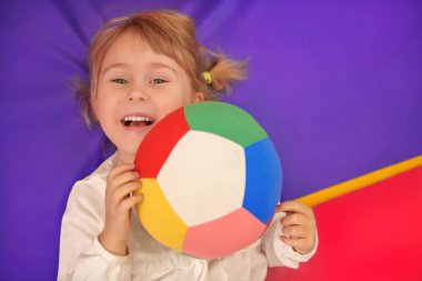 Mutlu çocuklar, çocuk oyunları. Sarı saçlı mutlu küçük bir kız oyun odasında neşeyle oynuyor. Anaokulu.