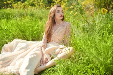 Yaz özgürlüğü. Güzel dantel elbiseli muhteşem bir kız güneşli bir günde yeşil çimlerin üzerinde dinlenir. Güzellik ve moda. 