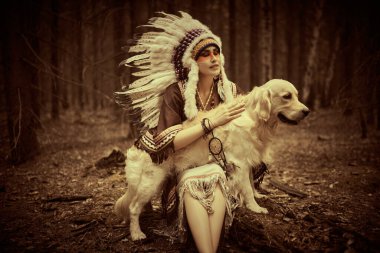 Geleneksel elbiseli ve tüylü başlıklı güzel bir Amerikalı kız köpeğiyle ormanda oturuyor. Amerika 'nın tarihi ve etnik kültürü. Retro biçim portresi.