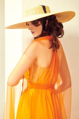Yaz modası. Zarif, çekici bir bayan, güzel bir turuncu elbisesi ve geniş kenarlı şapkasıyla bir yaz şehrinde duruyor. Yaz tatili.