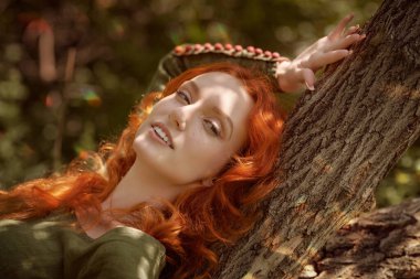 Eski Kelt zamanlarının tarihi yeniden yapılandırması. Geleneksel yeşil Kelt elbiseli güzel kızıl saçlı kız ormanda güneşli bir günün tadını çıkarıyor. Fantezi kadın kahraman.