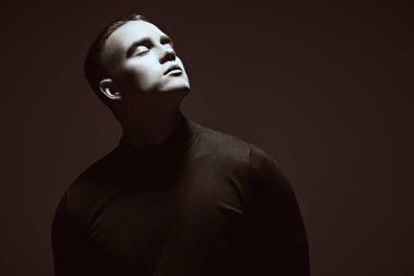 Kısa saçlı, siyah elbiseli, koyu gri bir stüdyoda poz veren vahşi bir gencin sanat portresi. Bir adamın psikolojisi. Boşluğu kopyala.