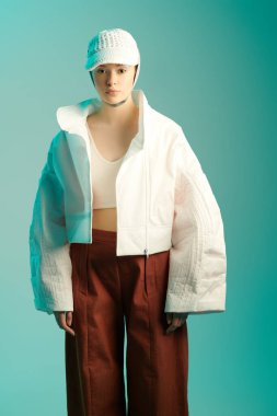 Moda özel tasarım koleksiyonu. Geniş serbest kıyafet, büyük boy. Aquamarine stüdyosunun arka planında tasarımcı kıyafetleriyle poz veren güzel manken kız..