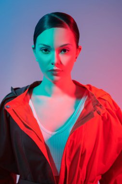 Yaz koleksiyonu. Modellik yapan bir kız şık turuncu bir manto giyiyor. Stüdyo görüntüsü karışık renk aydınlatması. 