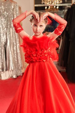 Lüks akşam tarzı. Çocukların tatil modası. Gece elbisesinde uzun kırmızı bir parti elbisesi içinde poz veren güzel bir kız modelin portresi..