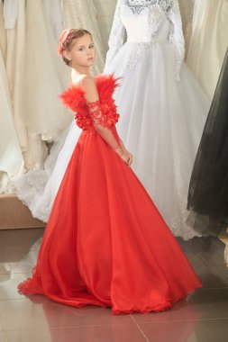 Lüks akşam tarzı. Çocukların tatil modası. Uzun kırmızı bir parti elbisesi içinde uzun bir gece elbisesinde poz veren sevimli bir kız modelin tam boy portresi..