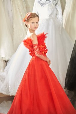 Lüks akşam tarzı. Uzun kırmızı bir parti elbisesi içinde uzun bir gece elbisesinde poz veren güzel bir kız modelin tam boy portresi. Çocukların tatil modası. 