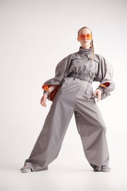 Beyaz bir stüdyo arka planında gri bir takım elbiseyle poz veren güzel bir kadın mankenin tam boy portresi. Yüksek moda. Gelecekçi Moda Biçimi.