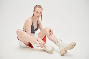 Siyah örgü bir şort ve beyaz bir şortla beyaz bir stüdyo arkasında poz veren güzel sarışın manken kız. Özel tasarım. Gençlik sporları yaz stili.